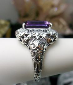 Natural Purple Amethyst Ring Intricate Design#149 Custom Made Inspired by Victorian era designs, I now offer this lovely filigree reproduction in sterling silver. This is a flawless natural purple amethyst is 12mm by 10mm in Length & Width. The ring is 3/4th of an inch North/South on the finger. The inside of the band is etched 925. Notice the intricate and detailed Victorian design of the antique patina silver filigree setting all the way down the band. This is an exquisite rendition of an Purple Amethyst Ring With Intricate Design For Promise, Purple Amethyst Promise Ring With Intricate Design, Elegant Purple Amethyst Ring With Intricate Design, Art Deco Purple Amethyst Ring For Anniversary, Purple Promise Ring With Intricate Design, Purple Amethyst Art Deco Ring For Anniversary, Purple Intricate Design Promise Ring, Purple Anniversary Rings With Intricate Design, Elegant Purple Amethyst Ring With Filigree