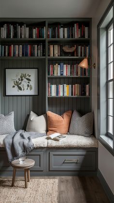 a bookshelf filled with lots of books next to a window and a bench