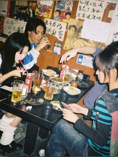 a group of people sitting around a table eating food and drinking drinks in front of them