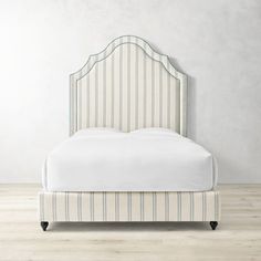 an upholstered bed with white and blue striped linens on the headboard