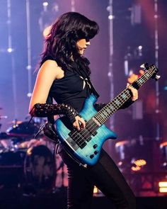 a woman holding a blue guitar on stage