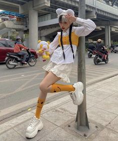 a woman dressed as a sailor leaning against a pole on the side of the road