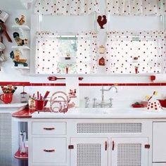 a white kitchen with red accents and polka dots on the wall above the countertop