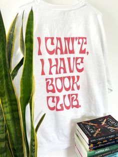 i can't have book club shirt next to some books and a potted plant