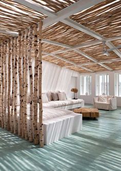 a living room filled with white furniture and lots of birch trees in the ceiling area