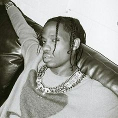 a black and white photo of a young man with dreadlocks sitting on a couch