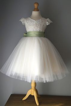 a white dress on a mannequin stand with a green sash around the waist