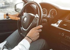 a person driving a car with their hand on the steering wheel and holding onto his wrist