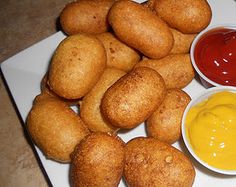 some fried food on a white plate with sauces and ketchup in small bowls