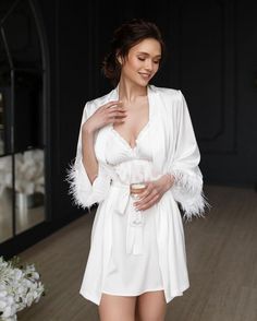 Make your bridal party feel luxurious and pampered with our White Feather Bride Robe Set! Each set includes delicate bridesmaid robes with a matching nightdress for the bride. The bride's nightgown and robe feature stunning feather sleeves for a touch of glamour. This elegant and stylish set makes the perfect bridesmaid gift to show your appreciation for your closest friends on your special day. Let your bridal party relax in style and comfort with this sophisticated White Feather Bride Robe Set Elegant Satin Robe With Feathers, Feathered Robe For Wedding Night, Elegant Robe With Feather Trim For Wedding Night, Elegant Wedding Robe With Feathers, Wedding Satin Robe With Feathers, Wedding Satin Dress With Feather Trim, Satin Wedding Dress With Feather Trim, Elegant Satin Robe For Honeymoon, Elegant Feather Trim Dress For Wedding Night