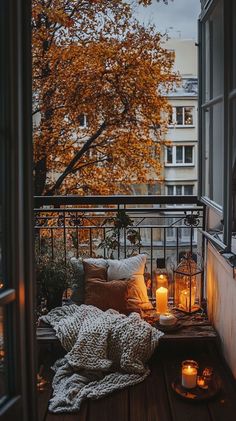 an apartment balcony with candles and blankets on the floor, next to a large window