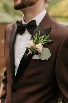 a man wearing a suit and bow tie with flowers on it's lapel