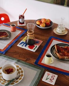 a wooden table topped with plates of food and cups of coffee next to each other