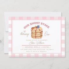 a pink and white checkered card with a stack of pancakes on it