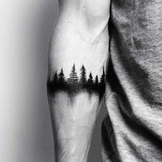 a man with a forest tattoo on his arm