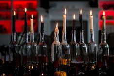 several wine bottles with candles in them sitting on a table