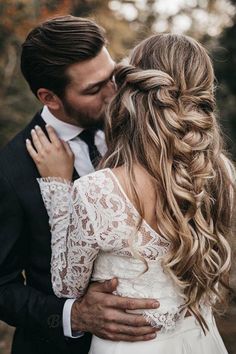 a man in a suit and tie kissing a woman with long hair on her shoulder