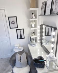 a room with a chair, mirror and pictures on the wall above it that is lit up