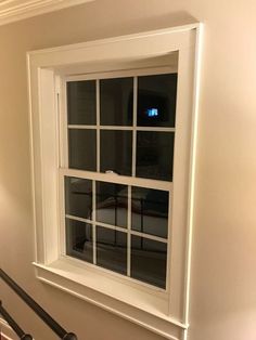 a white window sitting on the side of a wall next to a stair casement