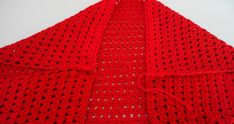 a red crocheted blanket is laying on the floor