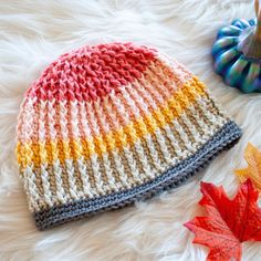 a multicolored knitted hat laying on top of a white furnishing