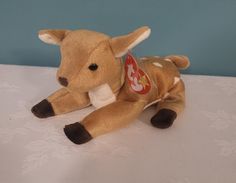 a small stuffed animal laying on top of a white tablecloth covered surface with a blue wall in the background