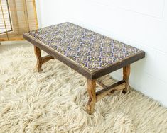 a wooden bench sitting on top of a shaggy rug next to a wall and window