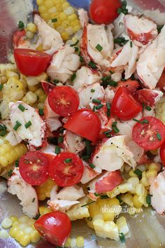 a salad with tomatoes, corn and scallops is shown in close up view