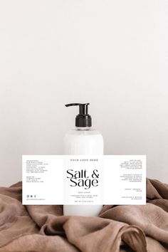 a bottle of soap sitting on top of a bed next to a brown blanket with a label that says salt and sage