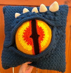 someone is holding up a crocheted pillow with an image of a monster's eye