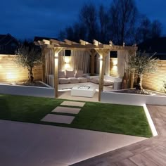 an outdoor living area is lit up at night with lights on the walls and grass