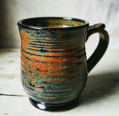 a black and orange coffee cup sitting on top of a table