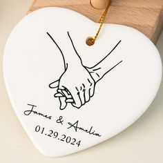 a white heart shaped ornament with two hands holding each other's hand