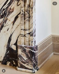 the corner of a room with marbled walls and wood flooring