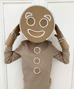 a person wearing a cardboard head covering their eyes and hands with an emoticive expression