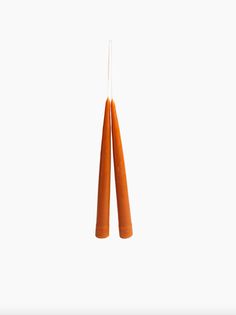 two orange candles hanging from strings against a white background