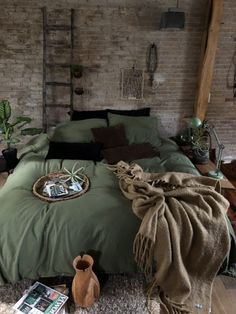 a bedroom with brick walls and green comforter on the bed, surrounded by plants