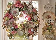 a wreath is hanging on the wall in front of a window with plates and dishes