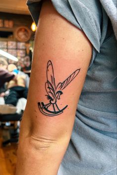 a tattoo on the arm of a woman with a bird and arrow in black ink