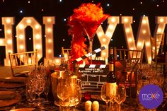 a table set up with wine glasses, champagne flutes and an orange feathered centerpiece