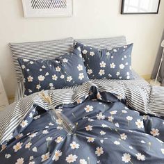 a bed covered in blue and white sheets with flowers on the comforter, next to a window