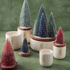 small christmas trees in ceramic bowls on a green surface with candle holders and candlesticks