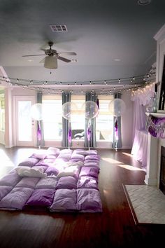 a living room filled with lots of purple furniture and decor on top of a hard wood floor