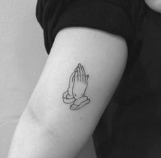 a black and white photo of a woman's arm with a praying hand tattoo