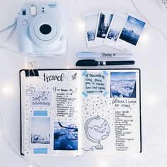 an open travel planner with polaroid camera and other items on the table next to it