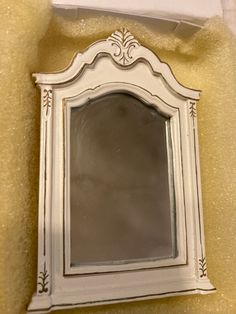 a white mirror sitting on top of a wall next to a yellow cloth covered floor