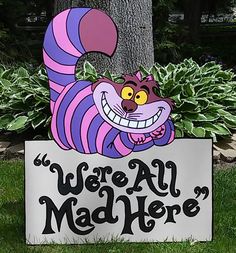 a sign that says we're all mad here with a cartoon cat on it