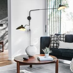 a living room with a couch, coffee table and two lamps on the wall above it