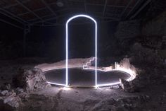 an illuminated object in the middle of a dirt area with rocks and trees around it