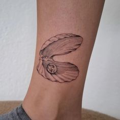 a woman's foot with a shell tattoo on the side of her leg,